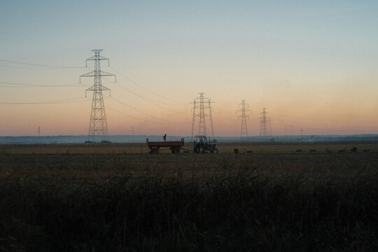 Wide horizon at sunset with tractor and power lines