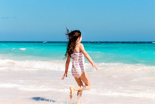 Child runs into the waves on a Bahamas beach while on vacation
