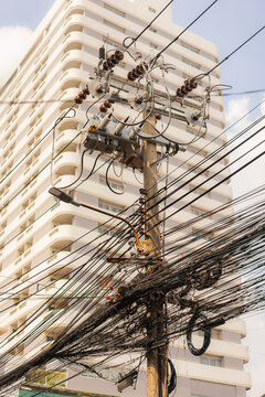 Utility pole with chaotic electric wires in fast growing city