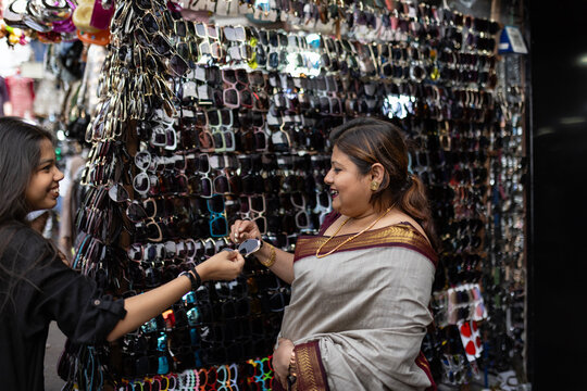 Indian mother and daughter trying fashionable sunglasses in the street