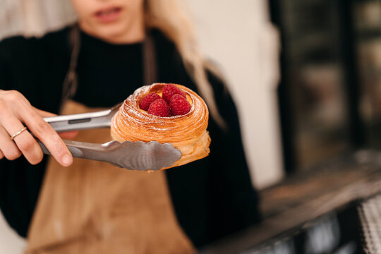 Bakery Worker Serves a Pastry With Raspberry Topping