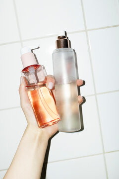 Hand holding beauty products pump bottles with hard direct flashlight