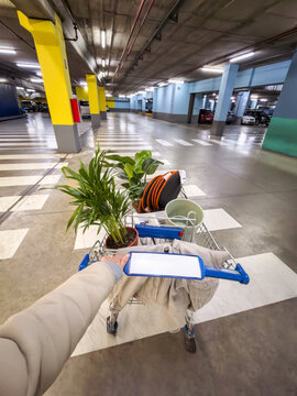 Woman pushing shopping cart with home decor in underground parking