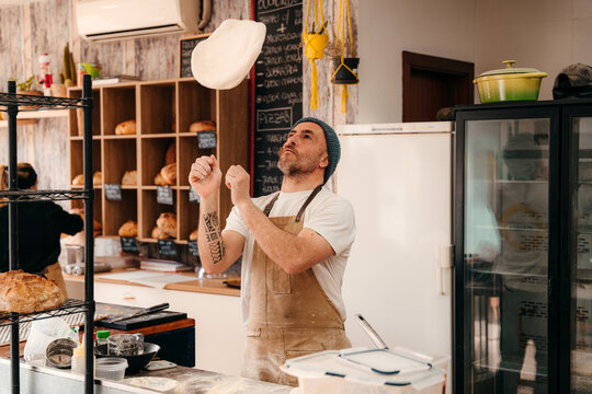 Baker Tossing Dough in Bakery During Afternoon Hours