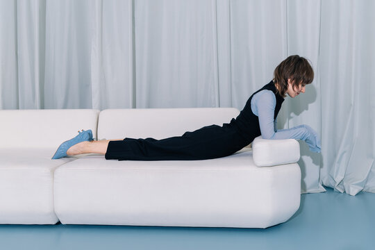 Minimal fashion pose woman lying on sofa in modern interior