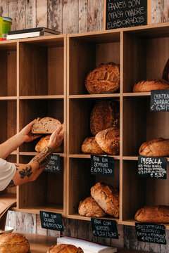 Baker Places Bread on a Shelf in a Bakery