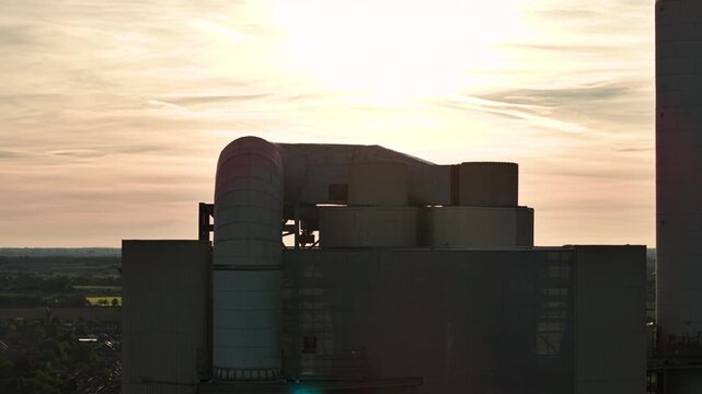 Aerial view of the industrial pipes and structures of the Rugby Cement Plant during a hazy sunset in Rugby, England, United Kingdom.