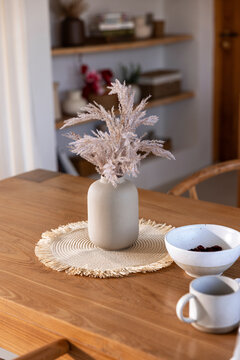 Neutral tones, vase, pampas grass, bowl, and mug on table.
