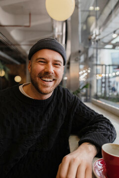 Cheerful customer smiling and enjoying coffee inside a modern cafe
