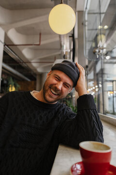 Laughing man enjoying coffee in cozy modern cafe