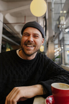 Laughing man enjoying hot beverage during break
