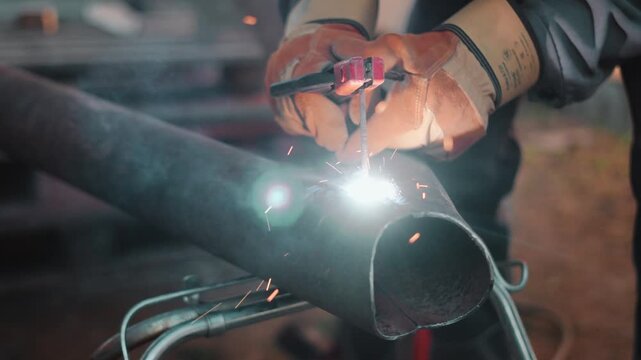 Closeup of bright welding arc illuminating steel pipe during industrial fabrication work. Skilled technician performs reliable metal joining process with precision and protective equipment.