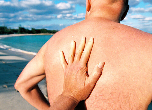 POV View of woman's hand on man's back on tropical beach