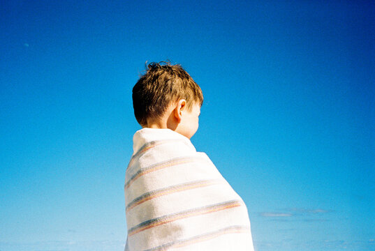 Boy at beach wrapped up in towel