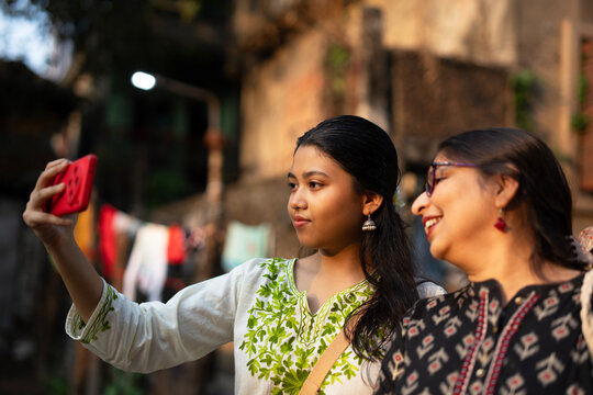 Mother and daughter standing and posing in front of smartphone