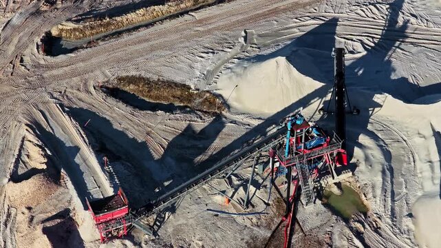 Industrial equipment sorting and transporting sand in an open pit mine quarry from above