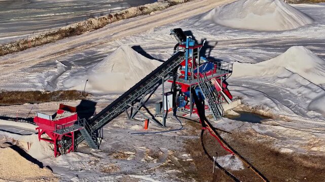 Sand quarry with sorting machinery processing aggregates on conveyor belts in aerial view