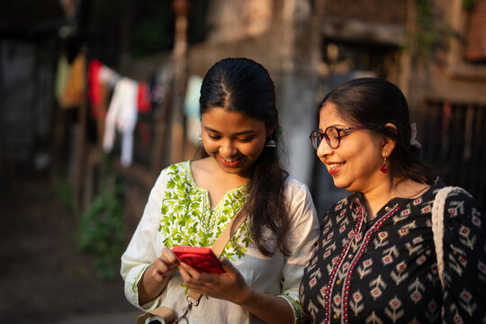 Mother and daughter standing and posing in front of smartphone