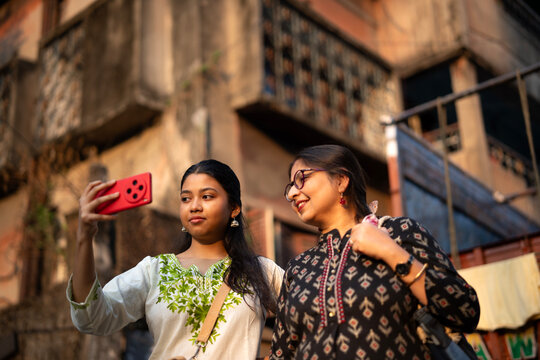 Mother and daughter standing and posing in front of smartphone