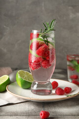 Glass of fresh raspberry lemonade with rosemary on grey tile table