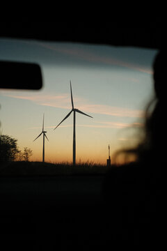 View from car in motion toward wind turbines at sunset