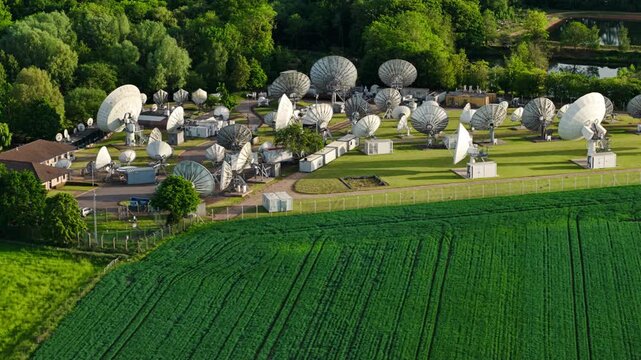 Aerial view of Satellite Mediaport Services with large parabolic antennas surrounded by lush green trees in Long Lawford, England, United Kingdom.