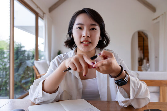 Woman with pen, notebook, and watch at desk.