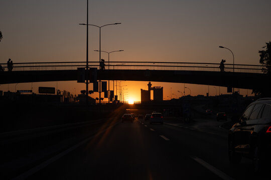 Cars driving under pedestrian bridge at sunset