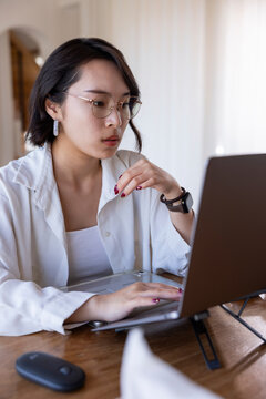 Woman with glasses working on a laptop.