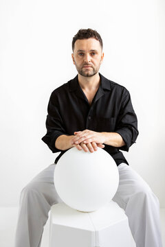 Man holds sphere in minimalist setting