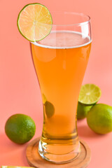 Fototapeta premium Glass of cold beer with lime on pink background