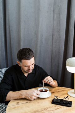 A man stirs his tea with a spoon.