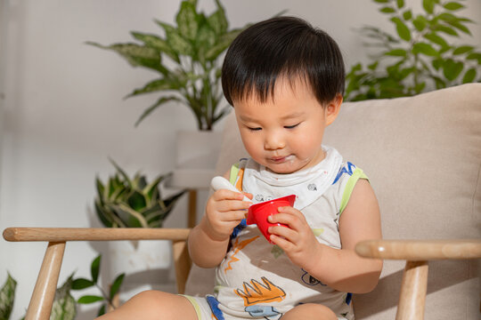 Adorable toddler enjoying a snack with yogurt on his face