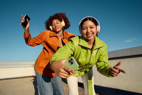 Friends taking selfie while listening to music outdoors