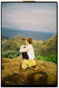 Hiker Takes a Break on Rocky Hilltop With Ocean View in Tenerife