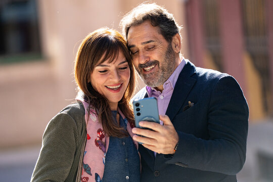 Mature couple enjoying date bonding over smartphone