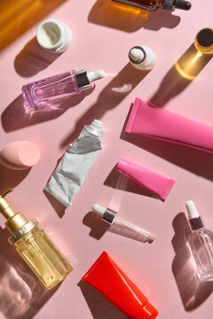Various Skincare Products Arranged on a Pink Table in Sunlight