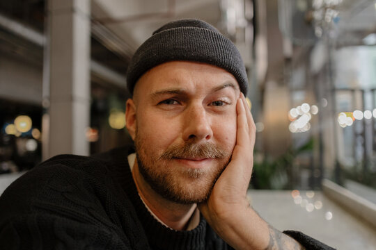 Creative man smiling looking at camera with hand on cheek