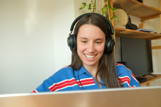 Smiling woman on video call using laptop and headphones
