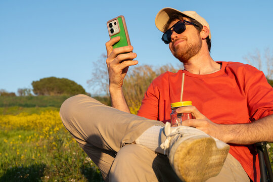 Man Enjoys Time Outdoors While Using Phone and Sipping Drink