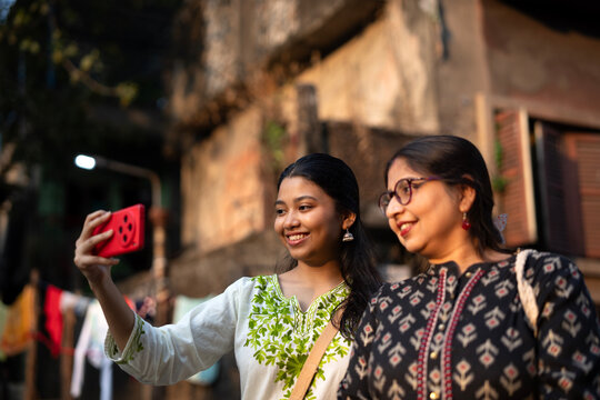 Mother and daughter standing and posing in front of smartphone