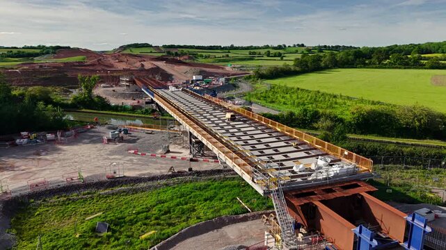 Aerial view of HS2 Project Civil Engineering Works bridge construction with steel girders and green fields in Southam, England, United Kingdom.