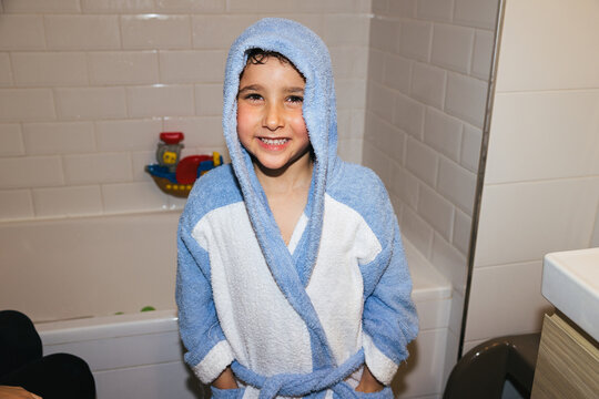 Happy kid enjoying bath time in blue bathrobe