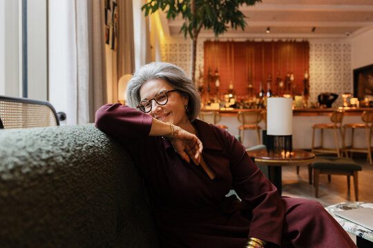 Smiling senior woman relaxing on a couch in a bar