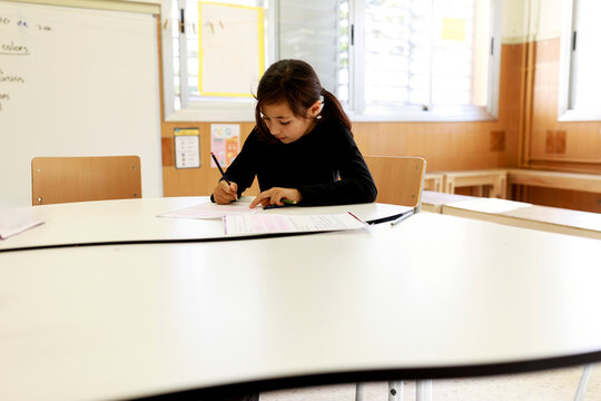 Child Writes in Classroom During School Lesson 