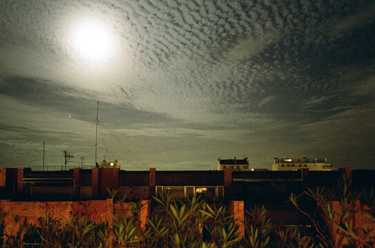 Night Sky View Over Rooftops With Clouds and Full Moon