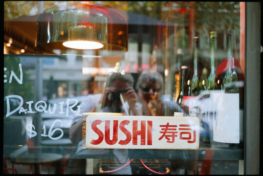 Sign for Sushi Restaurant in City With Reflections in Window