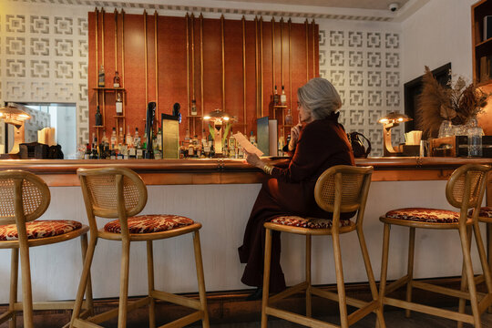 Senior woman looking at menu inside elegant bar