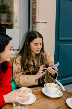 Friends enjoying coffee and a chat while using their cell phones