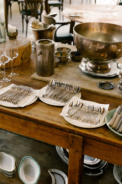 A wooden table is carefully arranged with refined tableware